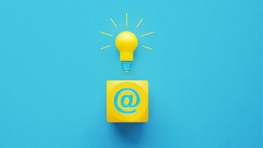 Light bulb sitting above a yellow cube with at symbol on turquoise background. Innovation and emailing concept. Horizontal composition with copy space.